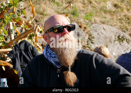 Mann mit langem Bart lächelt und genießt die letzten Sonnenstrahlen im Herbst beim Erntedankfest Stockfoto