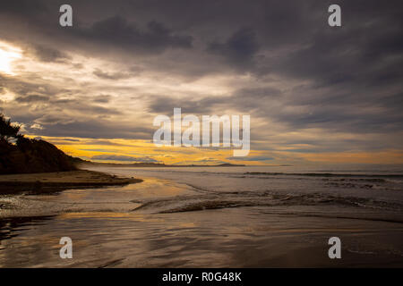 Die Wellen drücken, bis der Sandstrand in der Flussmündung bei Sonnenuntergang Stockfoto
