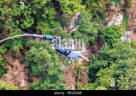 Sochi, Russland - Juni 7, 2015: Mann mit go pro Kamera am Handgelenk springen 207 Meter bei AJ Hackett Bungy Sky Park auf dem Berg Wald Hintergrund. Extreme ac Stockfoto