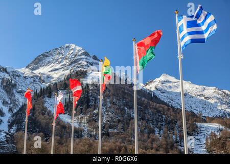 Flaggen von Griechenland, Weißrussland, Litauen und anderen Ländern Wave in der Wind als Symbol der Freundschaft auf verschneiten Bergen Peak und blauer Himmel. Verschiedene Stockfoto