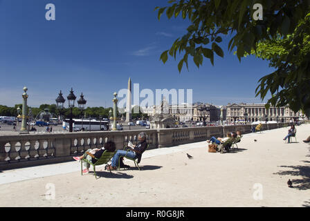 Leute, entspannen Sie sich an einem sonnigen Tag in den Tuilerien Gärten mit Blick auf den Place de la Concorde, dem größten Platz in Paris, Frankreich. Stockfoto