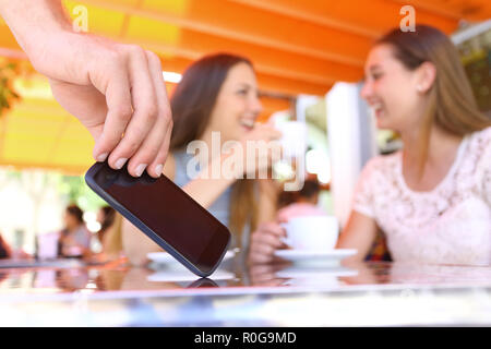 Abgelenkt Freunde sprechen in einer Bar und Nahaufnahme der Hand ein Dieb Diebstahl Telefon in Vordergrund Stockfoto