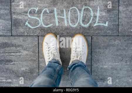 Das Wort Schule auf dem Asphalt und die Füße der Schüler. Zurück zu Schule! Stockfoto