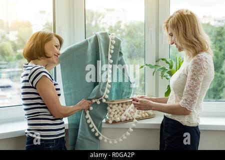 Interior Designer zeigt Proben von Stoffen und Zubehör für Vorhänge im neuen Haus. Bild im Hintergrund. Stockfoto
