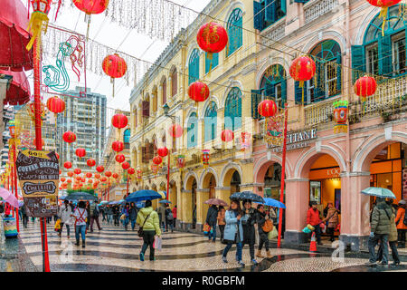 Macau, China - Januar 24, 2016: Touristen mit Sonnenschirmen Spaziergang entlang Senado Platz Straße dekoriert mit roten Laternen zum chinesischen Neujahrsfest celebratio Stockfoto