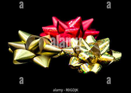 Drei (3) Weihnachten Satinschleife Bänder - 1 Gold-, 1 rot, 1 Gold Hologramm in der Farbe Schwarz Hintergrund. Zimmer für Kopieren. Stockfoto