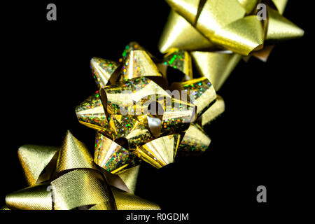 Drei (3) Weihnachten Satinschleife Bänder Gold und Gold Holographic in Farbe. Schwarzen Hintergrund. Zimmer für Kopieren. Stockfoto