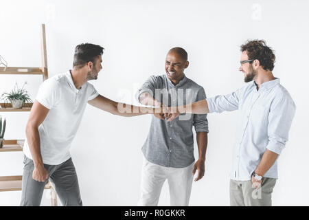 Multiethnische Gruppe der jungen Unternehmer halten sich an den Händen zusammen Stockfoto