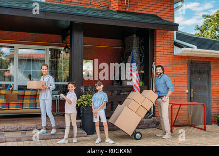 Eltern mit Kartons und Kinder in Country House stehen, bewegen Home Konzept Stockfoto