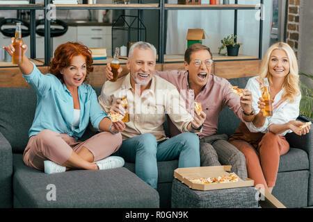 Aufgeregt reifen Freunden Bier trinken und essen Pizza zu Hause Stockfoto