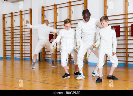 Sorgfältige ernste positive jungen Fechter aufmerksam zuhören, um professionelle Effiziente freundlich fechten Trainer im Fitnessstudio konzentriert Stockfoto