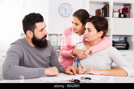 Junge Eltern Unterzeichnung Papiere für Scheidung, während ihre Tochter zu Hause Innenraum Stockfoto