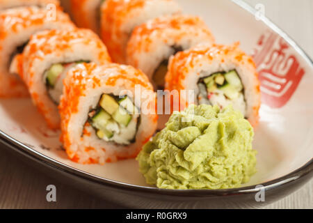 Close up Wasabi und Sushi rollen - Uramaki Kalifornien im Hintergrund. Japanische Küche. Geringe Tiefenschärfe. Fokus auf Wasabi Stockfoto