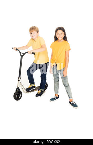 Hohe Betrachtungswinkel der glückliche Kinder stehen mit Scooter und lächelnd in die Kamera isoliert auf weißem Stockfoto