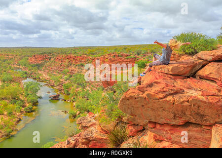 Gerne blonde Frau mit offenen Armen auf roten Sandsteinfelsen an den Falken Head Aussichtspunkt über Murchison River im Kalbarri Nationalpark, Western Australia. Freiheit kaukasischen Reisende genießen Outback von Australien Stockfoto