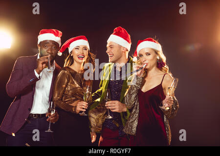 Aufgeregt multikulturellen Freunde in santa Hüte mit Champagner Gläser Stockfoto