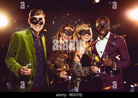 Glamouröse multiethnischen Freunde im Karneval Masken holding Champagner Gläser und feiern das neue Jahr auf Party Stockfoto