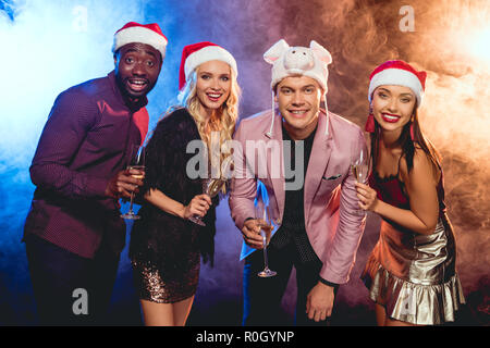 Fröhlich multikulturellen Freunde in santa Hüte feiert das neue Jahr mit Sekt Gläser auf Party Stockfoto