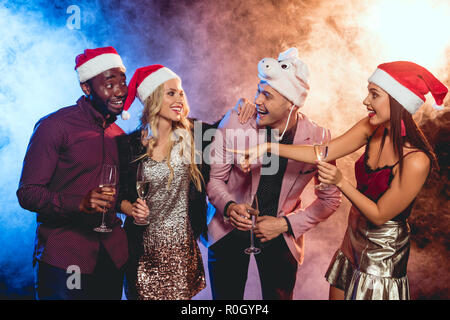 Aufgeregt multikulturellen Freunde in santa Hüte mit Champagner Gläser auf Neues Jahr Partei Stockfoto