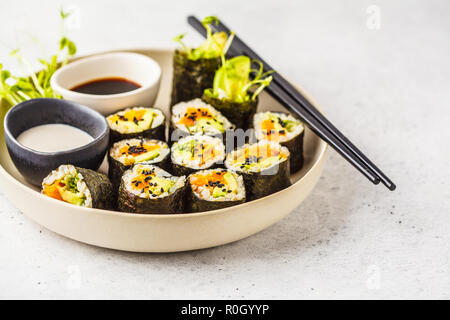 Vegane sushi Rollen mit Kürbis, brauner Reis und Avocado. Auf Basis pflanzlicher Ernährung Lebensmittel. Stockfoto