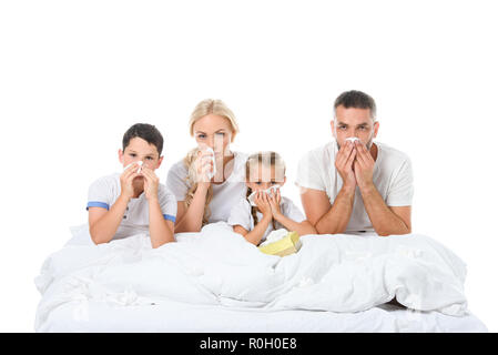 Kranke Familie mit runny Nasen holding Servietten während Sie im Bett sitzen, isoliert auf weißem Stockfoto