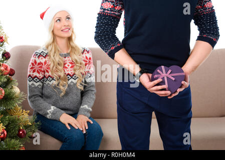 Frau suchen Bei man ausblenden herzförmige Weihnachten Geschenkbox, isoliert auf weißem Stockfoto