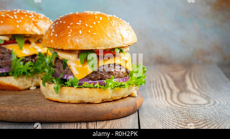 Zwei frische hausgemachte Burger mit Bratkartoffeln auf einem Holztisch. Mit kopieren. Stockfoto