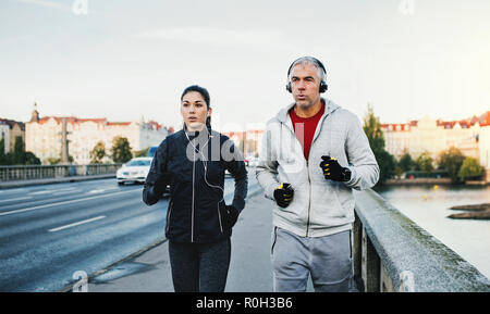 Ein paar mit Kopfhörer läuft draußen auf der Brücke in Prag City. Stockfoto