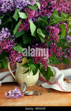 Schönen Komposition mit Blumenstrauß der Flieder und die Uhr Stockfoto