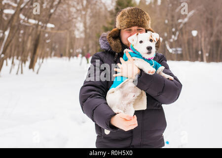 Tierbesitzer, Hund und Menschen Konzept - Young lächelnd kaukasischen Mann, hält Jack Russell Terrier im Freien im Winter. Stockfoto