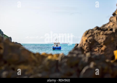 Landschaft Erfassung von Boot auf dem Meer, in der Bucht vor Anker, Weich-Fokus schroffen Felsen im Vordergrund, vom Strand entfernt. Insel Skomer Landung Boot. Stockfoto