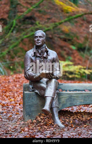 Statue des Dichters Robert Burns sitzt auf der Bank im Herbst am Birks O'Aberfeldy Scenic Area in Aberfeldy, Perthshire, Schottland, Großbritannien Stockfoto