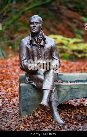 Statue des Dichters Robert Burns sitzt auf der Bank im Herbst am Birks O'Aberfeldy Scenic Area in Aberfeldy, Perthshire, Schottland, Großbritannien Stockfoto