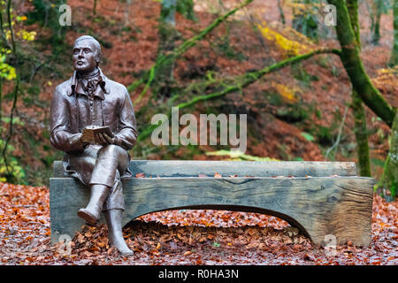 Statue des Dichters Robert Burns sitzt auf der Bank im Herbst am Birks O'Aberfeldy Scenic Area in Aberfeldy, Perthshire, Schottland, Großbritannien Stockfoto