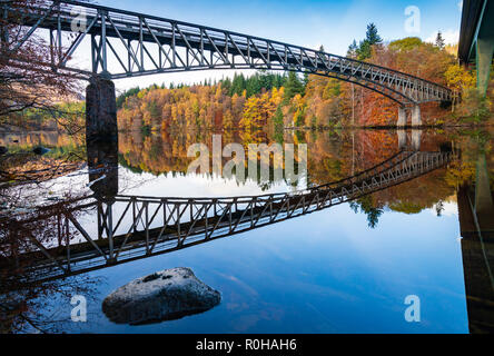 Spektakuläre späten Herbst Baum Farben und Brücke ist in den Gewässern des Loch Faskally in Pitlochry, Perthshire, Schottland, UK wider. Stockfoto