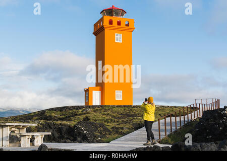 SNAEFELLSNES, ISLAND - August 2018: Frau im gelben Regenmantel, Bild von Svortuloft Leuchtturm. Stockfoto