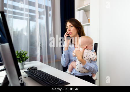 Beschäftigte Geschäftsfrauen in einem Büro arbeiten mit einem Baby auf Ihre Hände. Stockfoto