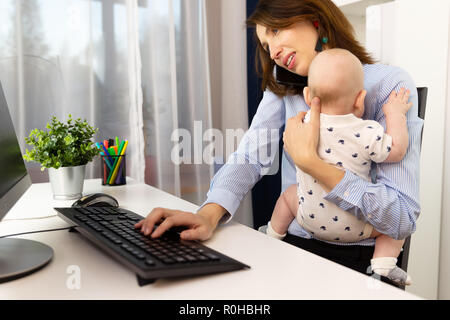 Beschäftigte Geschäftsfrauen in einem Büro arbeiten mit einem Baby auf Ihre Hände. Stockfoto