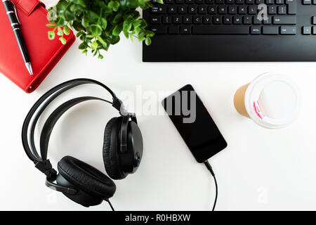 Kopfhörer und Office Tools auf einem weißen Hintergrund. E-Learning - Konzept. Stockfoto
