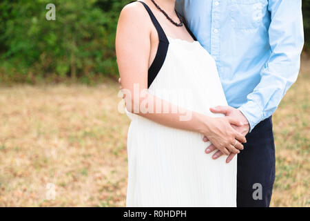 Mans und Frauen arm liegend auf Bauch der schwangeren Frau Stockfoto