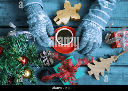 Blue Theme topview Touristische tragen Sie Handschuhe und heißen Kaffee Tasse auf Holz Tisch, die Geschenke Weihnachten Thema dekorieren halten Stockfoto