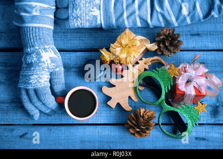 Blue Theme topview Touristische tragen Sie Handschuhe und heißen Kaffee Tasse auf Holz Tisch, die Geschenke Weihnachten Thema dekorieren halten Stockfoto