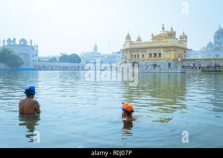 Nicht identifizierbare Punjabi Sikhs Nihang pilgrim Anhänger "Krieger" mit Badewanne und Gebet in Teich und Meditieren vor Golden Temple (Harmandir Sahib) Stockfoto