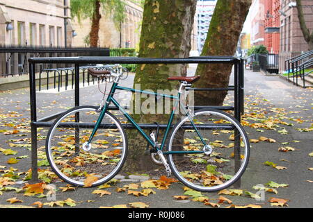 Rennrad und alten Baum im Herbst mit einer in einem alten Gebäude im Hintergrund Stockfoto