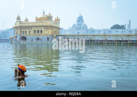 Nicht identifizierbare Punjabi Sikhs Nihang pilgrim Anhänger "Krieger" mit Badewanne und Gebet in Teich und Meditieren vor Golden Temple (Harmandir Sahib) Stockfoto