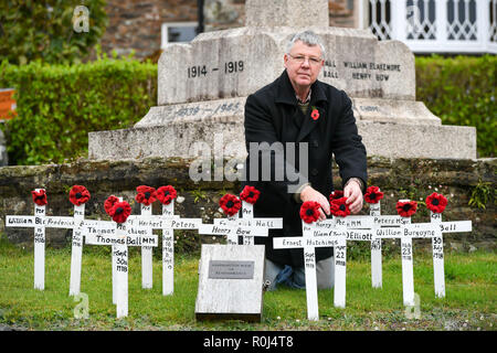 Gemeinderat Laurence Grüne neigt dazu, von Hand gefertigte hölzerne Kreuze und handgestrickte Mohnblumen, die auf dem Kriegerdenkmal in der Devonshire Dorf Ashprington, wo er die kleine Gedenkstätte mit Kreuzen, die im Großen Krieg aus der Ashprington Pfarrei gestorben geschmückt hat, platziert sind. Die Dorfbewohner dazu neigen, die Gedenkstätte und haben ein Buch mit Details der Gemeindemitglieder, die serviert und starb während des Ersten Weltkrieges. Stockfoto