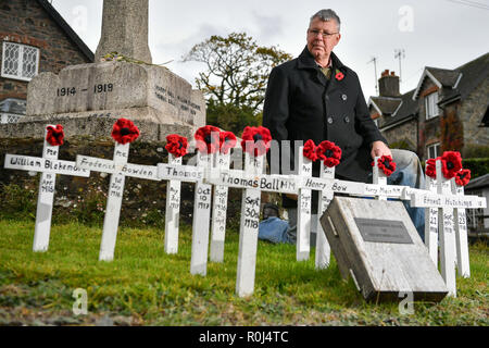 Gemeinderat Laurence Grüne neigt dazu, von Hand gefertigte hölzerne Kreuze und handgestrickte Mohnblumen, die auf dem Kriegerdenkmal in der Devonshire Dorf Ashprington, wo er die kleine Gedenkstätte mit Kreuzen, die im Großen Krieg aus der Ashprington Pfarrei gestorben geschmückt hat, platziert sind. Die Dorfbewohner dazu neigen, die Gedenkstätte und haben ein Buch mit Details der Gemeindemitglieder, die serviert und starb während des Ersten Weltkrieges. Stockfoto