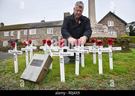 Gemeinderat Laurence Grüne neigt dazu, von Hand gefertigte hölzerne Kreuze und handgestrickte Mohnblumen, die auf dem Kriegerdenkmal in der Devonshire Dorf Ashprington, wo er die kleine Gedenkstätte mit Kreuzen, die im Großen Krieg aus der Ashprington Pfarrei gestorben geschmückt hat, platziert sind. Die Dorfbewohner dazu neigen, die Gedenkstätte und haben ein Buch mit Details der Gemeindemitglieder, die serviert und starb während des Ersten Weltkrieges. Stockfoto