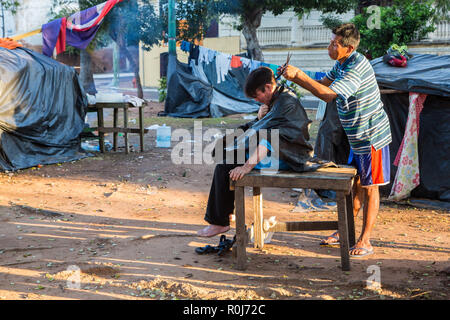 Einen Haarschnitt in den Slums von Asuncion Stadt. Friseur auf Straßen von Ciudad de Asunción, Paraguay. Zwei Männer, im Zelt. Stockfoto