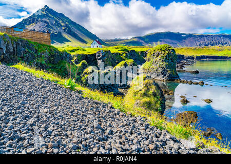 Vulkanische Landschaft von basaltgestein Formation mit einem schönen Haus und der Berg Stapafell bei Arnarstapi Fischerdorf in Island Stockfoto